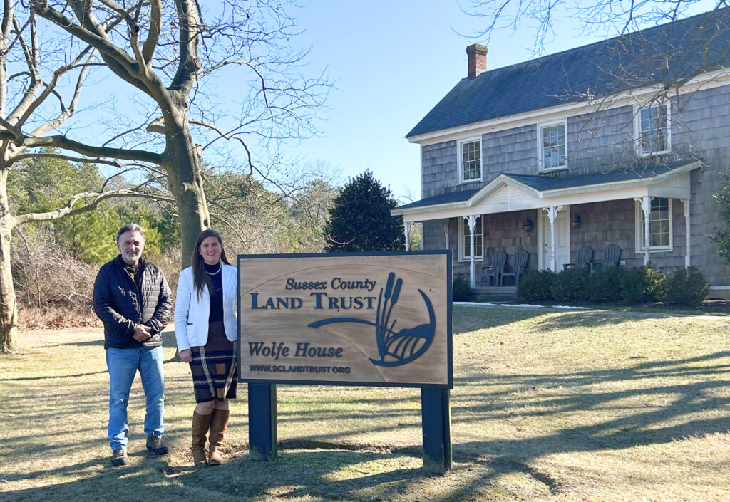 two people standing in front of historic home with land trust signage